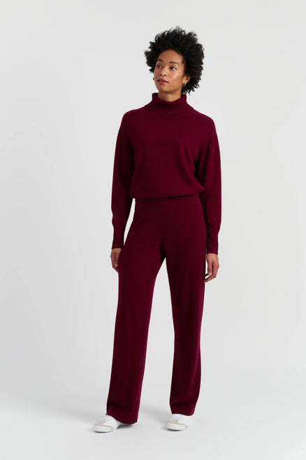 Person wearing a burgundy sweater and pants on a white background
