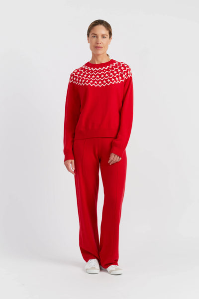 Person wearing a red sweater with a white pattern and matching pants on a white background