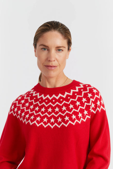 Woman wearing a red sweater with white pattern on a light gray background