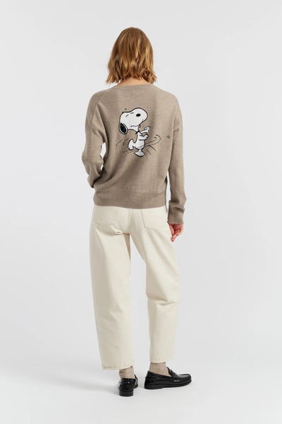 Person wearing a beige sweater with a dog graphic on the back, standing against a white background