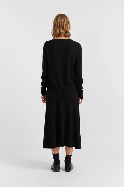 Person wearing a black sweater and skirt set on a white background