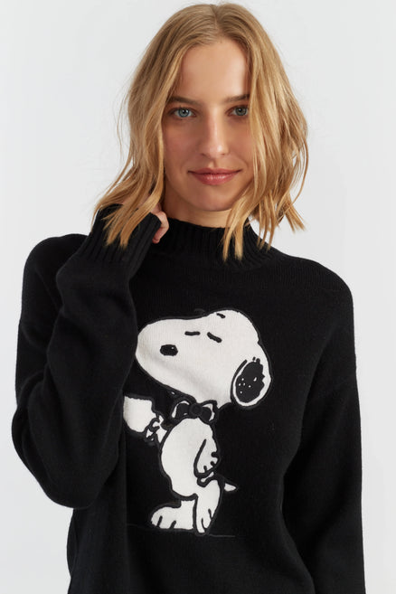 Person wearing a black sweater with a Snoopy graphic on a white background