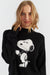 Person wearing a black sweater with a Snoopy graphic on a white background