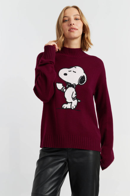 Woman wearing a burgundy sweater with a cartoon character on a plain background