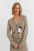 Woman wearing a beige cardigan with a cartoon character on a plain background