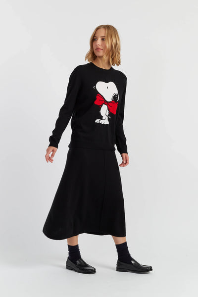Woman wearing a black sweater with a dog design and a long black skirt on a white background