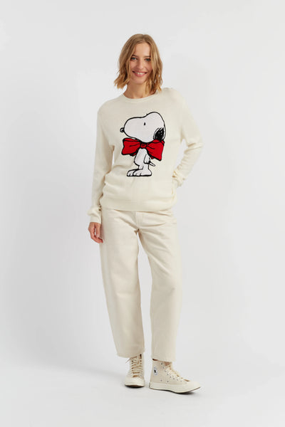 Woman wearing a cream-colored outfit with a Snoopy graphic on a white background