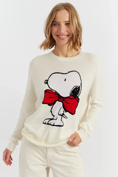 Woman wearing a white sweater with a cartoon character design on a plain background