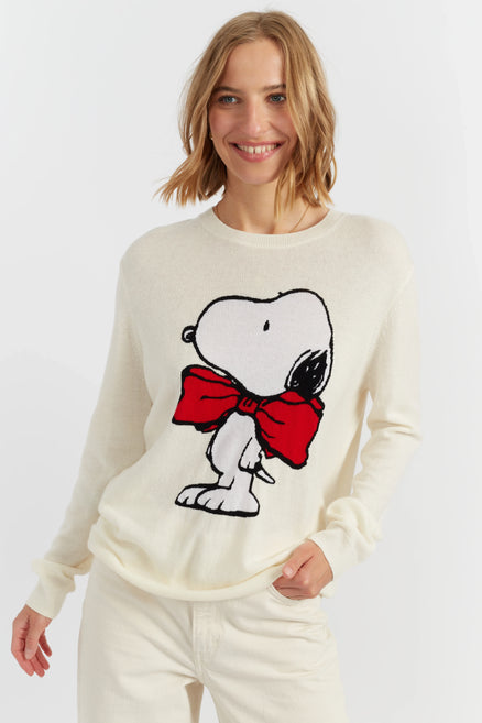 Woman wearing a white sweater with a cartoon character design on a plain background