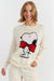 Woman wearing a white sweater with a cartoon character design on a plain background